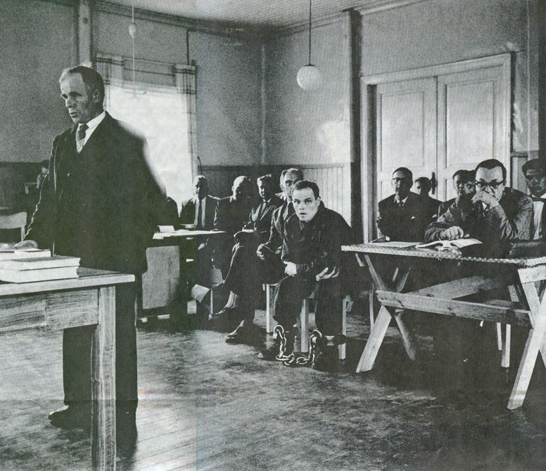 Рунар Хольмстрём (сидит посередине) на суде в Хейнявеси в 1960.  Один из последних подозреваемых в истории Финляндии, кого заковывали в такие кандалы