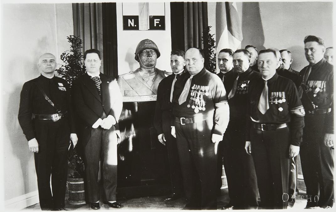 Делегация итальянских фашистов дарит IKL бюст Муссолини, 1935.  Увешанный медалями Косола потолстел и обрюзг.  Фото из вики